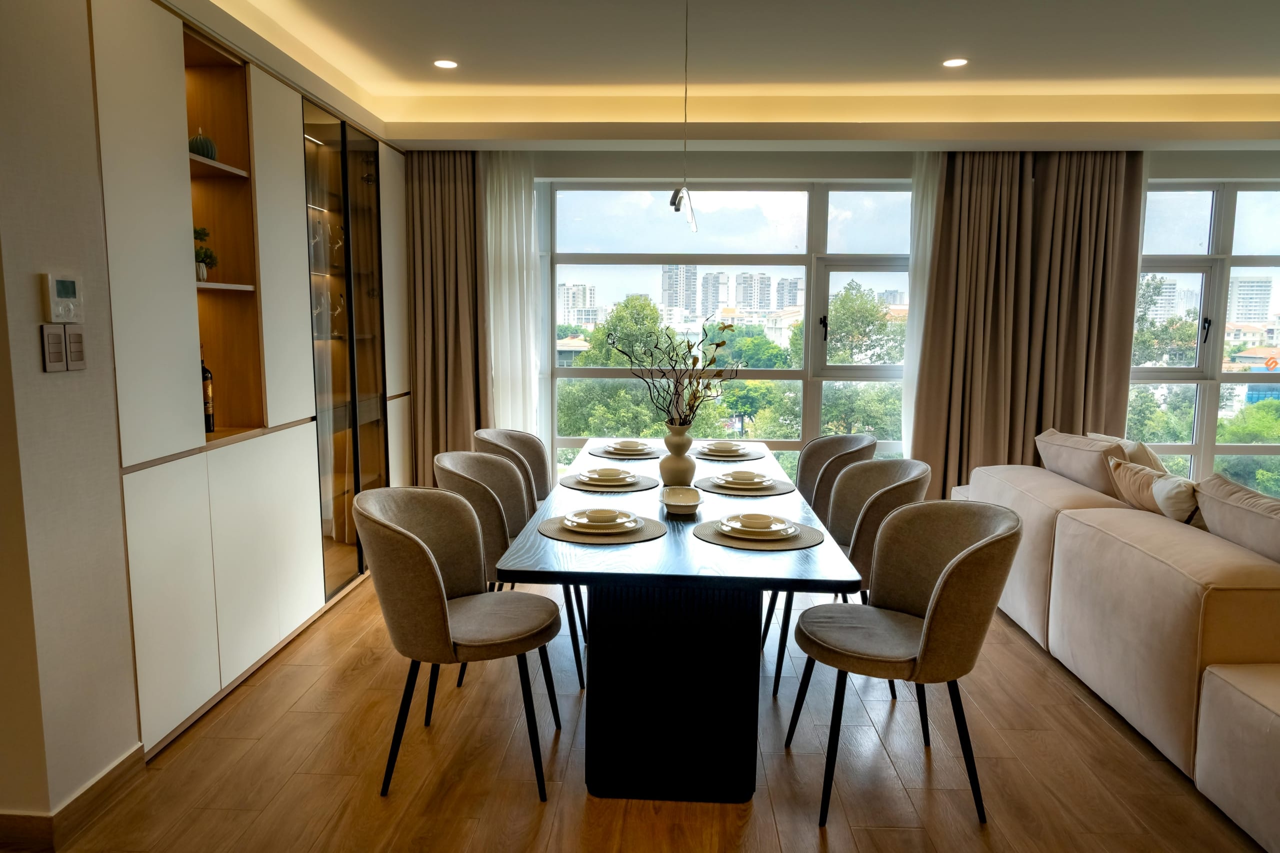 Elegant dining room with cityscape view, featuring table settings for eight.